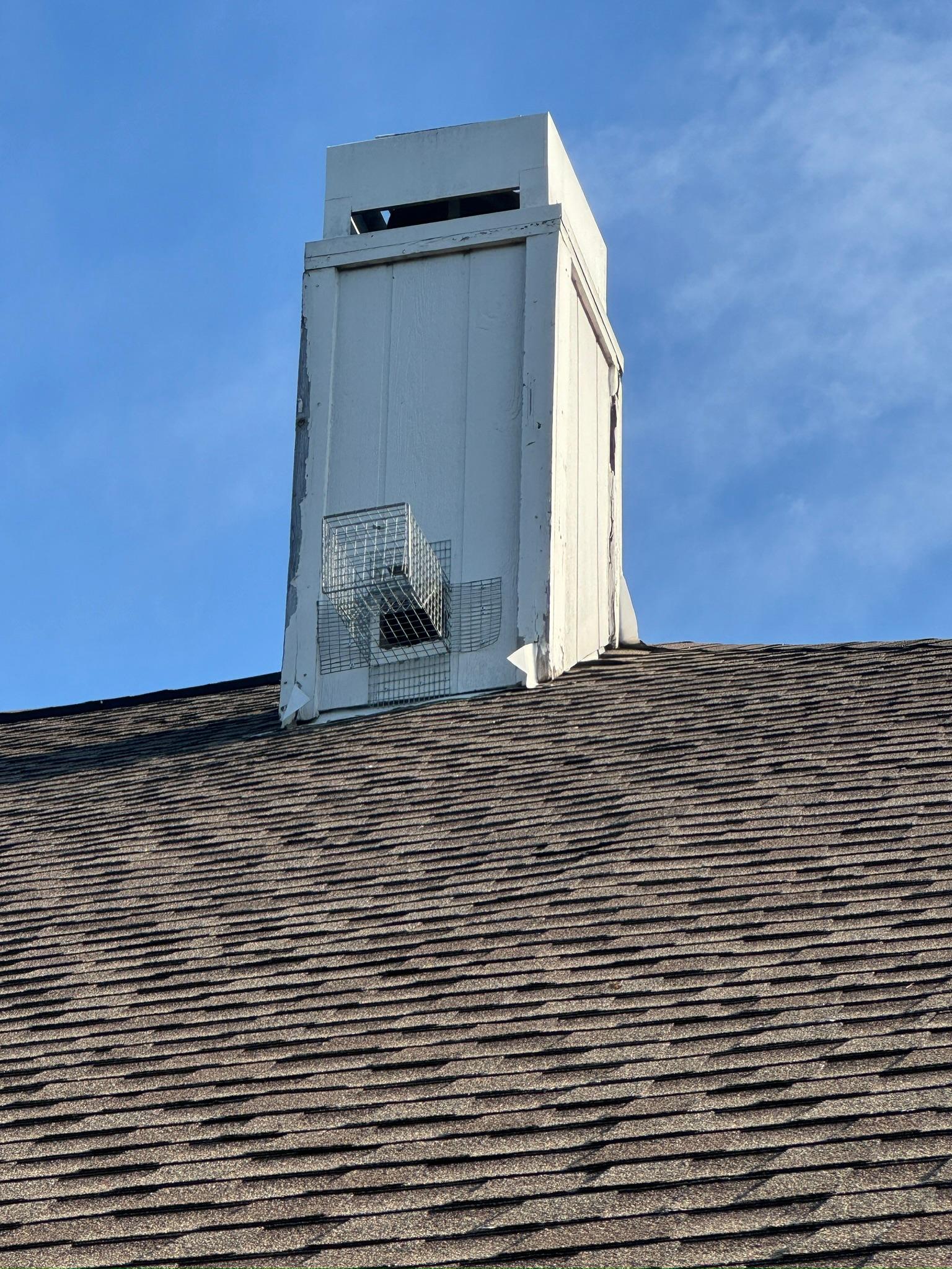 Wire exclusion device fitted to a siding-clad chimney above a roof