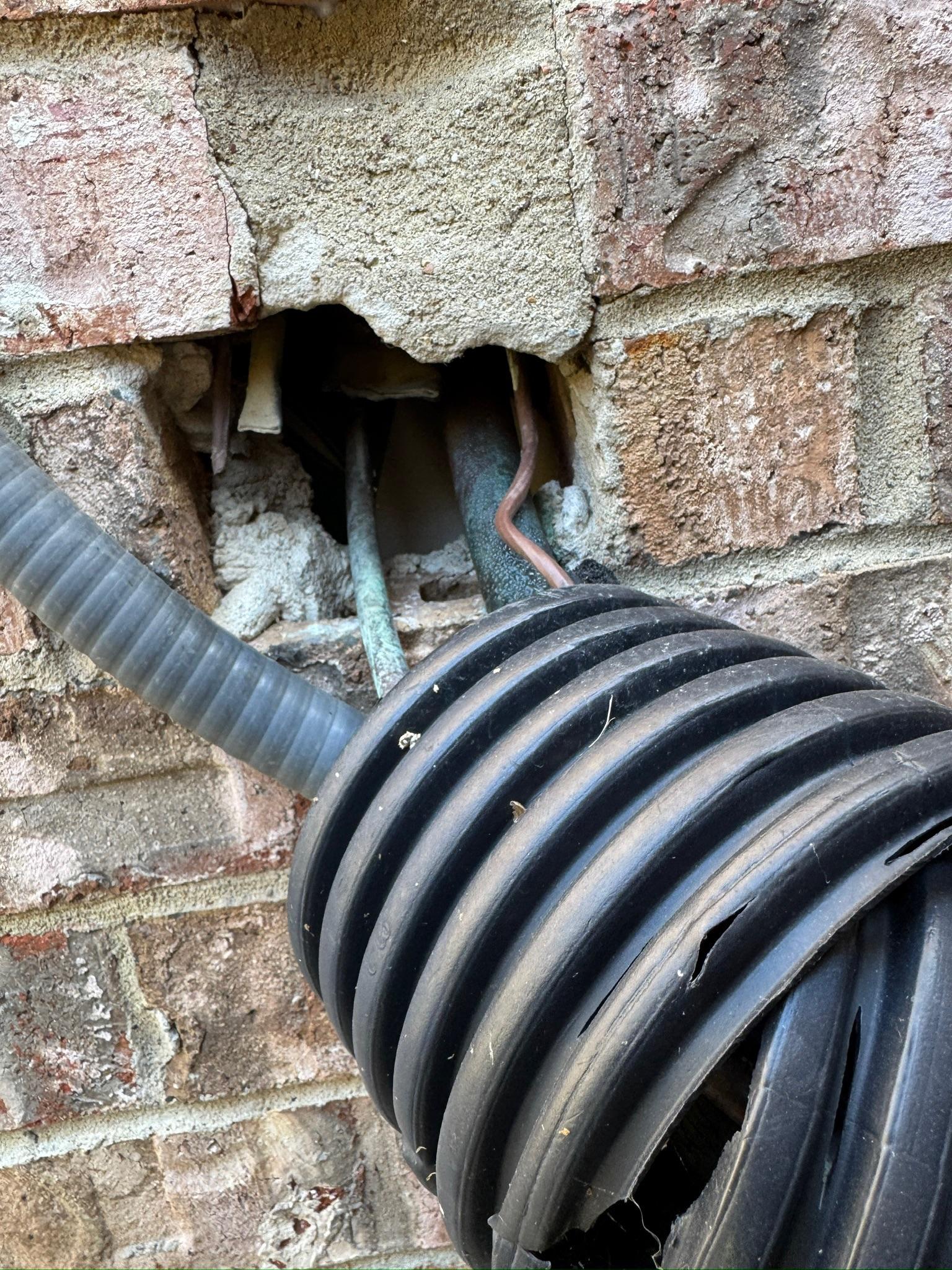 Unsealed opening in brickwork around utility lines and conduit