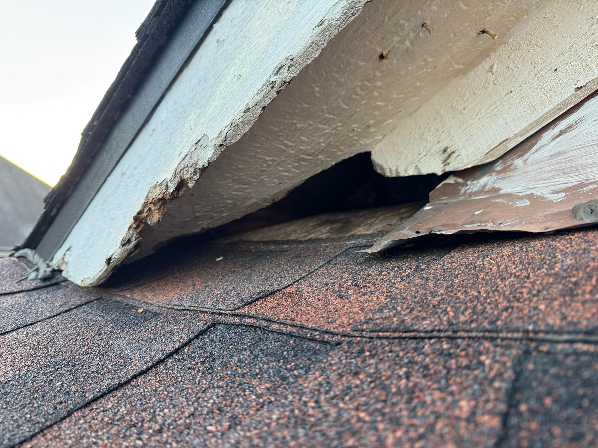 Separated soffit and trim leaving a dark opening above roof shingles