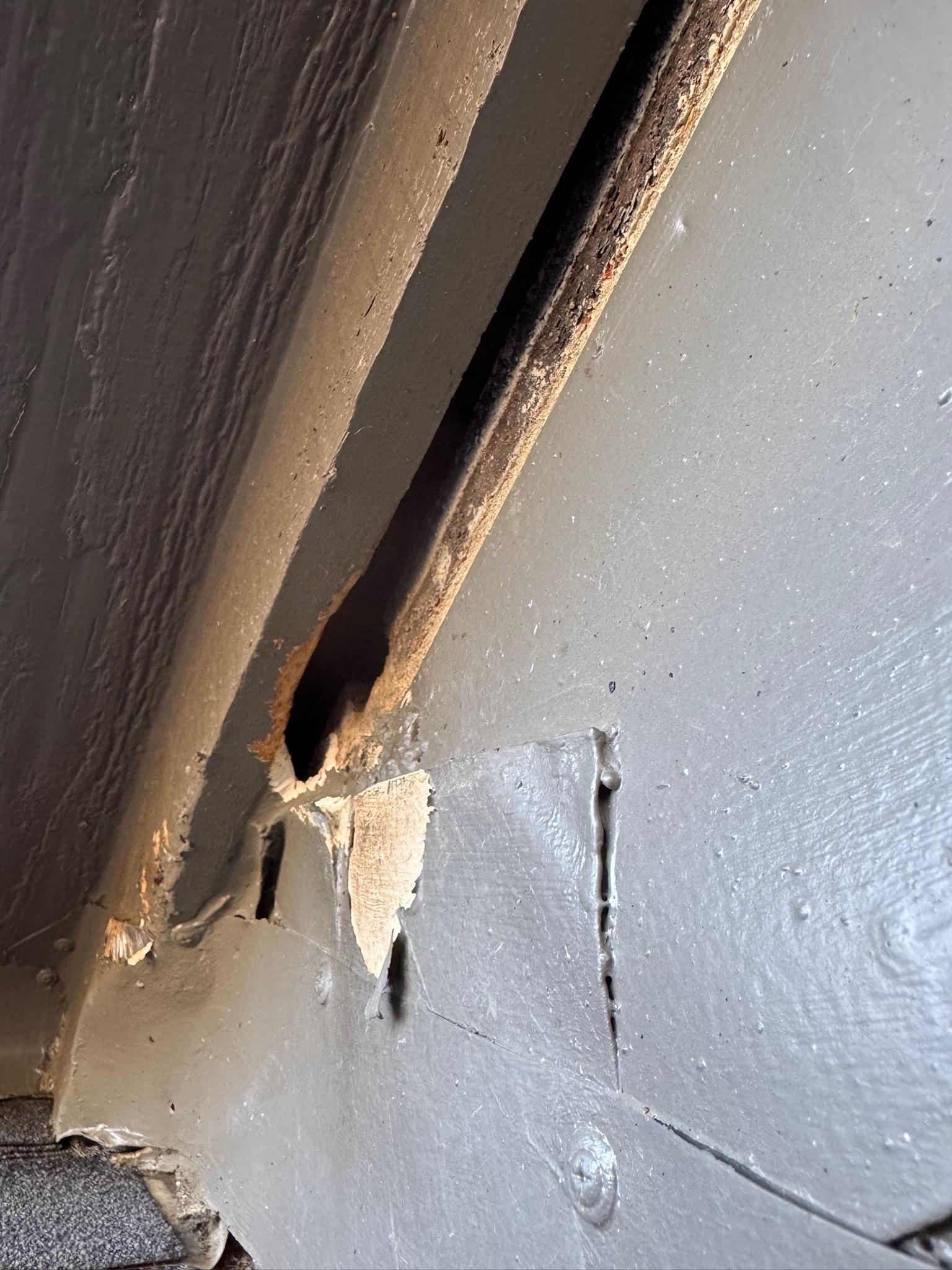 Broken trim and an opening beneath the eave of an exterior wall