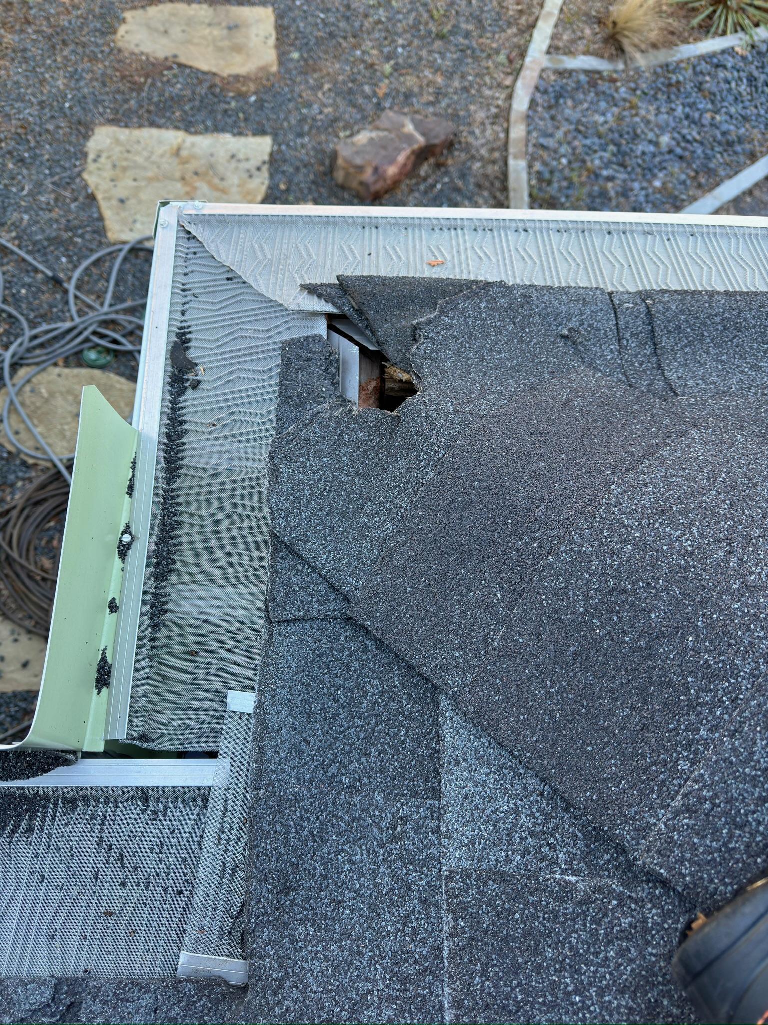 Exposed hole at the corner of shingles and white roof trim