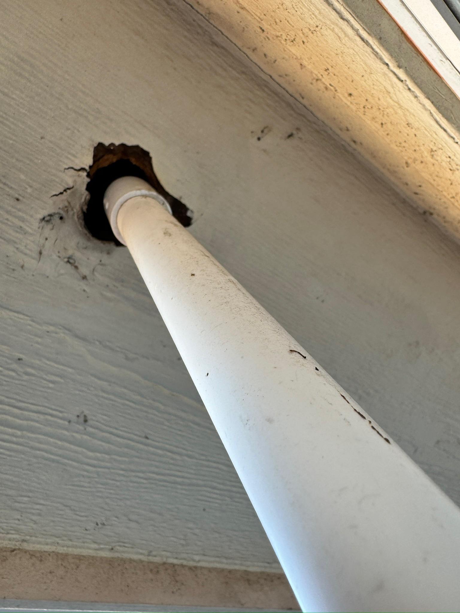 Gap in a soffit panel around a white pipe