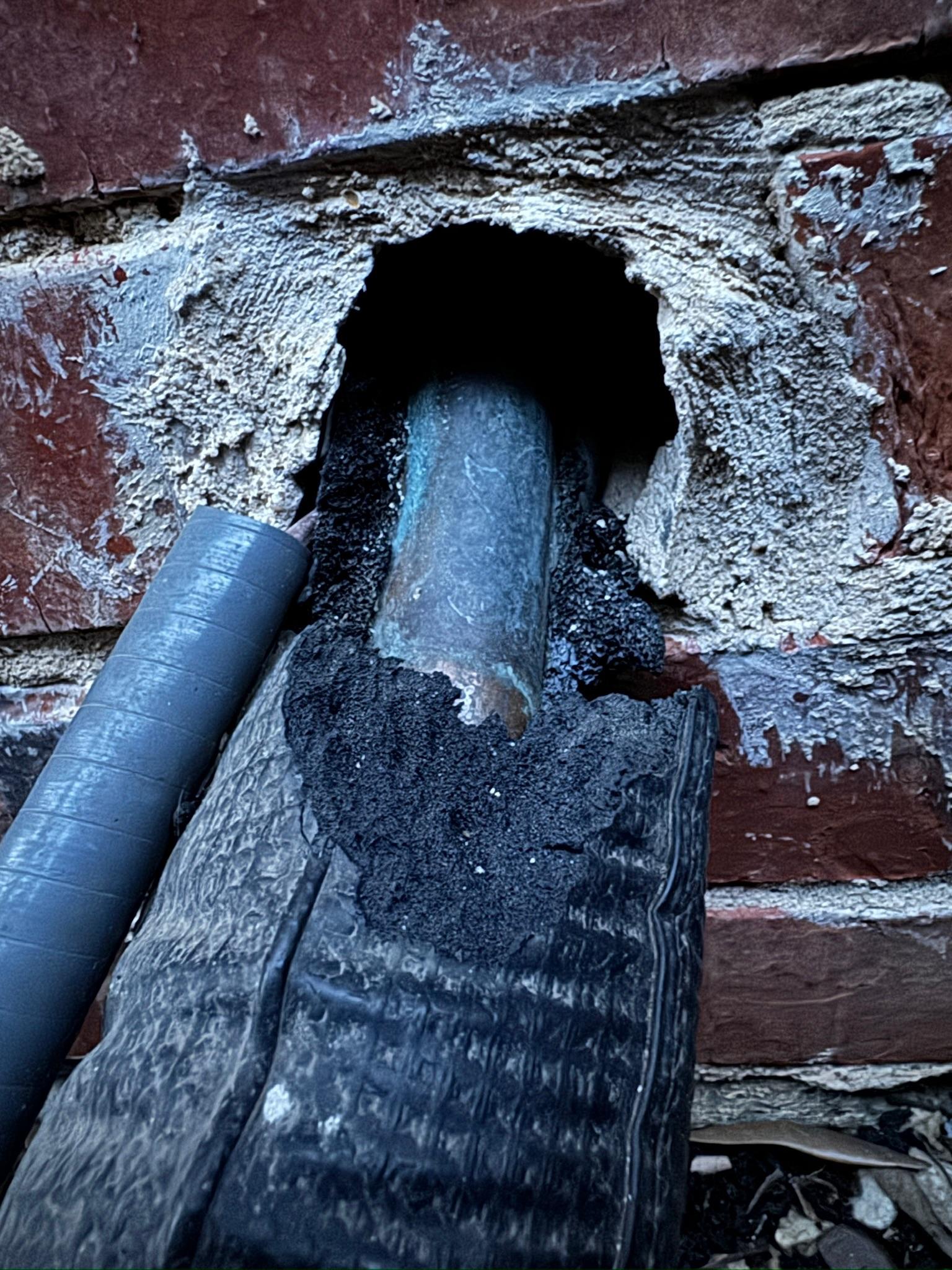 Gap in brickwork around an insulated exterior pipe